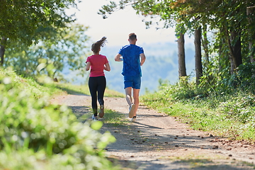 Image showing couple enjoying in a healthy lifestyle while jogging on a country road