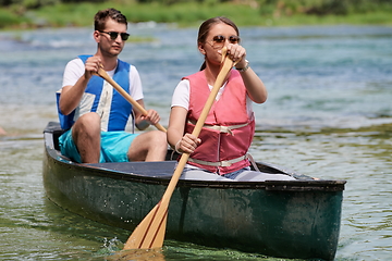 Image showing friends are canoeing in a wild river