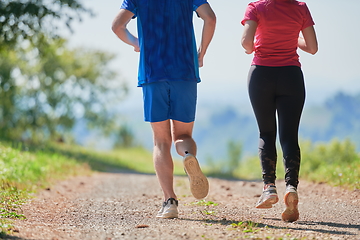 Image showing couple enjoying in a healthy lifestyle while jogging on a country road