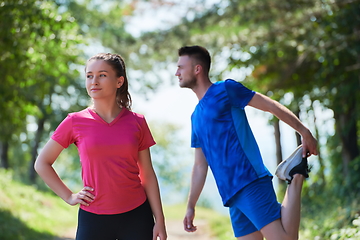 Image showing couple enjoying in a healthy lifestyle warming up and stretching before jogging