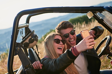 Image showing couple enjoying beautiful sunny day taking selfie picture while driving a off road buggy