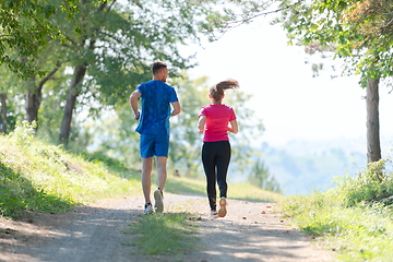 Image showing couple enjoying in a healthy lifestyle while jogging on a country road