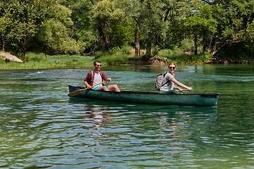 Image showing friends are canoeing in a wild river