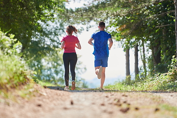 Image showing couple enjoying in a healthy lifestyle while jogging on a country road