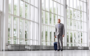 Image showing businessman with travel bag walking along office