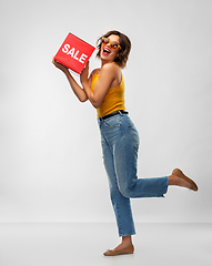 Image showing happy smiling young woman posing with sale sign