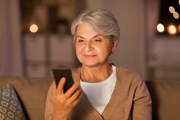 Image showing happy senior woman with smartphone at home