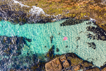 Image showing Woman laying in a beautiful rock pool in a ring donut floaty