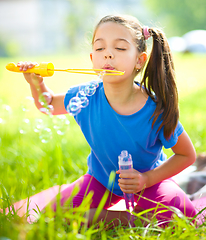 Image showing Little girl is blowing a soap bubbles