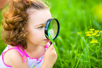 Image showing Young girl is looking at flower through magnifier