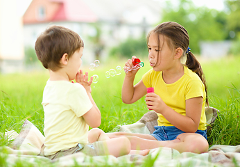 Image showing Little girl and boy are blowing soap bubbles