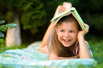Image showing Little girl is hiding under book outdoors