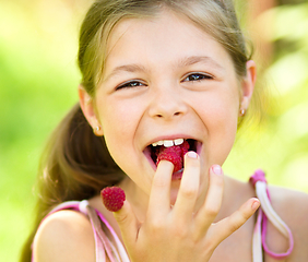 Image showing Young girl is holding raspberries on her fingers