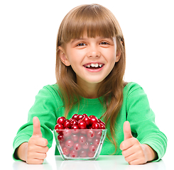 Image showing Cute girl is eating cherries showing thumb up sigh