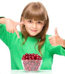 Image showing Cute girl is eating cherries showing thumb up sigh