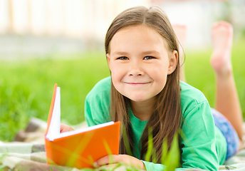 Image showing Little girl is reading a book outdoors