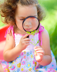 Image showing Young girl is looking at flower through magnifier