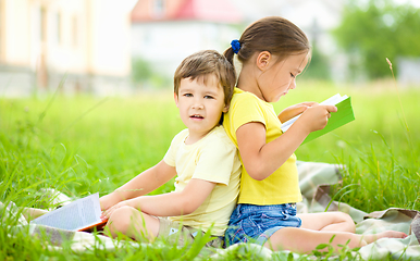 Image showing Little girl and boy are reading book outdoors