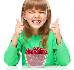 Image showing Cute girl is eating cherries showing thumb up sigh