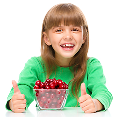 Image showing Cute girl is eating cherries showing thumb up sigh