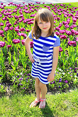 Image showing young girl stands by lilac tulips