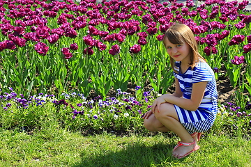 Image showing little girl sitd by lilac tulips