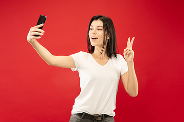 Image showing Caucasian young woman\'s half-length portrait on red background