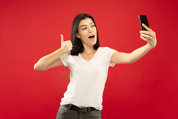 Image showing Caucasian young woman\'s half-length portrait on red background