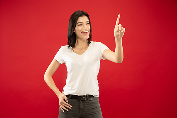 Image showing Caucasian young woman\'s half-length portrait on red background