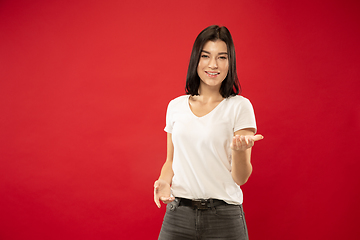 Image showing Caucasian young woman\'s half-length portrait on red background