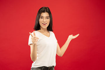 Image showing Caucasian young woman\'s half-length portrait on red background