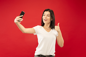 Image showing Caucasian young woman\'s half-length portrait on red background