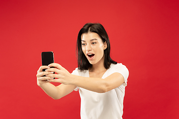 Image showing Caucasian young woman\'s half-length portrait on red background