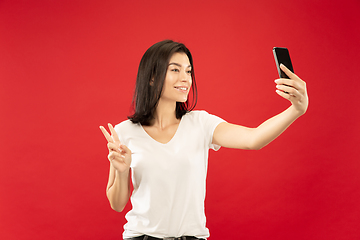 Image showing Caucasian young woman\'s half-length portrait on red background