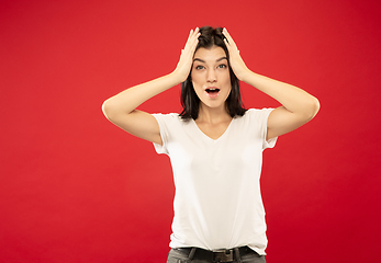 Image showing Caucasian young woman\'s half-length portrait on red background