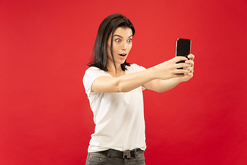 Image showing Caucasian young woman\'s half-length portrait on red background