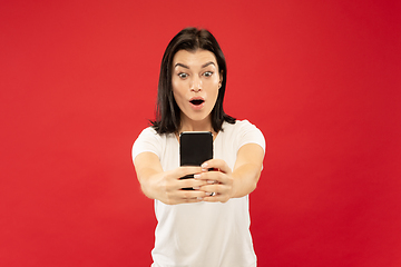 Image showing Caucasian young woman\'s half-length portrait on red background