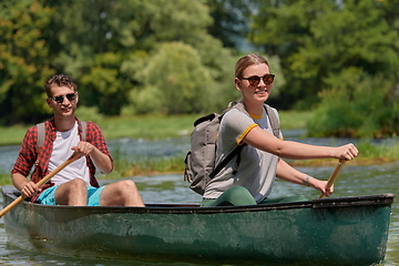 Image showing friends are canoeing in a wild river