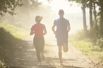 Image showing couple enjoying in a healthy lifestyle while jogging on a country road