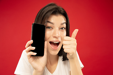 Image showing Caucasian young woman\'s half-length portrait on red background