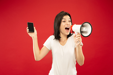 Image showing Caucasian young woman\'s half-length portrait on red background