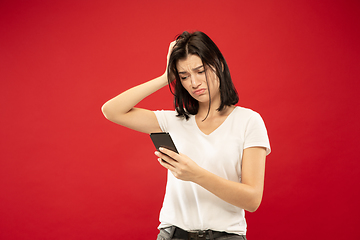 Image showing Caucasian young woman\'s half-length portrait on red background