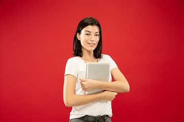 Image showing Caucasian young woman\'s half-length portrait on red background