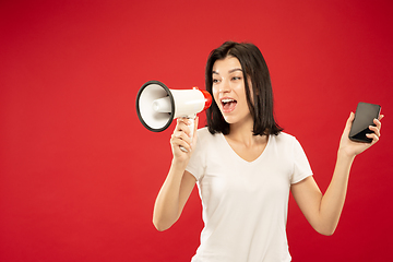 Image showing Caucasian young woman\'s half-length portrait on red background