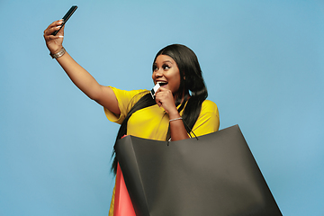 Image showing Young woman in dress shopping on blue background