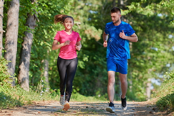 Image showing couple enjoying in a healthy lifestyle while jogging on a country road