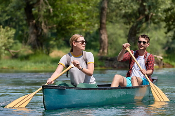 Image showing friends are canoeing in a wild river