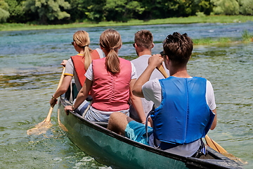 Image showing Group adventurous explorer friends are canoeing in a wild river