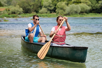 Image showing friends are canoeing in a wild river