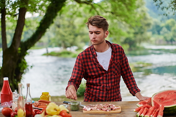 Image showing man putting spices on raw meat for barbecue